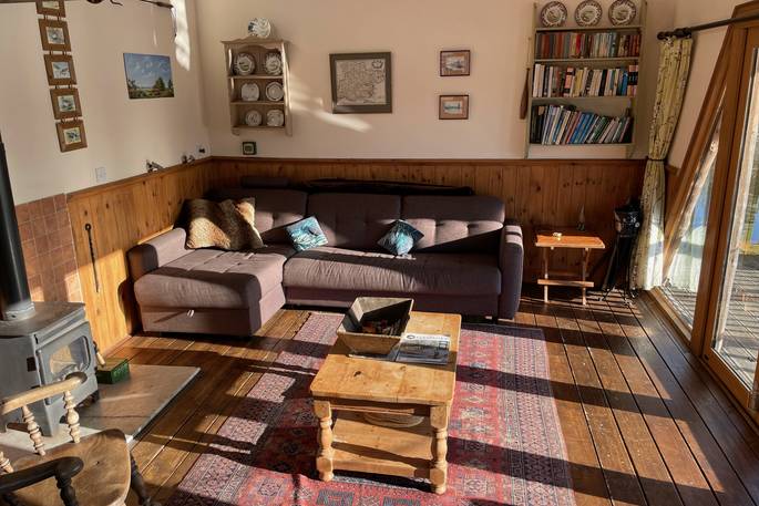 Living area with a large sofa and a wood burner as the main source of heat